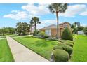 Charming single-story home featuring meticulously maintained landscaping with a green lawn, shrubbery, and mature palms at 13524 Glynshel Dr, Winter Garden, FL 34787