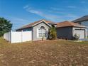 View of the exterior and fenced yard of a single-story home with a well manicured yard and a two-car garage at 212 Ashford Dr, Davenport, FL 33837