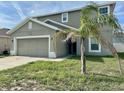 Two-story home featuring an attached two-car garage and a small palm tree in the front yard at 235 Hibiscus St, Winter Haven, FL 33881