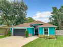 Charming turquoise home featuring a well-kept lawn, a dark grey garage door, and a cozy front porch at 2545 El Portal Ave, Sanford, FL 32773