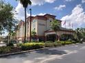 Exterior front view of Galleria Palms Hotel with palm trees, American flags, and manicured landscaping at 3000 Maingate Ln # 210, Kissimmee, FL 34747
