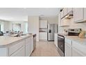 Well-lit kitchen with stainless steel appliances, white cabinets, and ample countertop space, open to the dining area at 3061 Moulin Rd, Davenport, FL 33837
