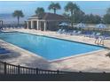 Inviting community pool with sun loungers and shade umbrellas, perfect for relaxation at 347 Ridgemark Ave, Groveland, FL 34736