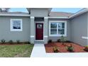 Welcoming front entrance with a red door, colorful plants, and a freshly manicured flower bed at 3498 Sw 131St Place Rd, Ocala, FL 34473