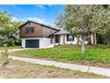 Two-story home with brown siding, white painted brick, black shutters, and freshly landscaped front yard at 7085 Willowwood St, Orlando, FL 32818