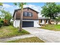 Two-story home with brown siding, white painted brick, attached garage, and some lawn shrubbery at 7085 Willowwood St, Orlando, FL 32818