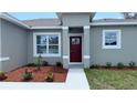 Charming single-story home showcasing a red front door, manicured landscaping, and a welcoming entrance at 851 Marion Oaks Mnr, Ocala, FL 34473