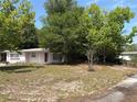 A single-story home is nestled behind mature trees and a spacious front yard at 128 N Sunland Dr, Sanford, FL 32773