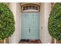 Inviting light blue double front doors are framed by symmetrical greenery and light neutral pillars on brick entryway at 140 Rangeline Woods Cv, Longwood, FL 32750