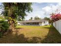 View of the rear of the house showing an enclosed porch and a spacious, grassy backyard at 1418 Oregon St, Orlando, FL 32803