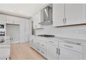 Contemporary kitchen with white cabinets, a gas stove top, and stainless steel range hood at 1461 Santorini Way, Tavares, FL 32778
