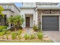 Charming home showcasing a landscaped front yard, stone accents, and a covered front entryway at 15702 Vetta Dr, Bella Collina, FL 34756