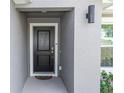 Inviting front entrance featuring a classic black door, modern lighting, and neutral gray walls at 1857 E Cooper Dr, Deltona, FL 32725