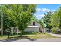 The property's exterior is partially obscured by trees and landscaping, featuring a white picket-style feature and a metal roof at 201 W Washington St, Minneola, FL 34715