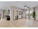 Bright and airy living room featuring light wood floors, built-in shelves, a ceiling fan, and large windows with elegant curtains at 209 Luxmore Rd, Groveland, FL 34736