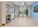 Inviting living space boasting a white bookcase, light wood floors, large windows with curtains, and an accent wall at 209 Luxmore Rd, Groveland, FL 34736