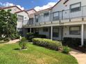 Attractive two-story condo building with well-manicured lawn, mature landscaping, and covered parking at 2524 Woodgate Blvd # 201, Orlando, FL 32822