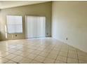 Spacious living room with tile floors, natural light from sliding glass door and a window at 2524 Woodgate Blvd # 201, Orlando, FL 32822