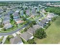An aerial view of a residential neighborhood with green spaces, sidewalks, and tree-lined streets at 2956 White Cedar Cir, Kissimmee, FL 34741