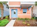 Close-up of a peach-colored home showcasing a blue front door, shutters, and well-manicured landscaping at 3062 Pirate Way, Kissimmee, FL 34747