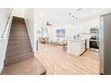 Open-concept living area featuring wood floors, stairs, stainless steel appliances and a dining area at 3062 Pirate Way, Kissimmee, FL 34747