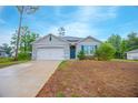 Well-maintained single-Gathering home featuring a two-car garage, pleasant landscaping, and a blue front door at 3479 Courtland Blvd, Deltona, FL 32738
