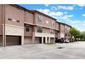 Shot of townhomes with tandem two-car garages, stone facade, and well-maintained landscaping at 6107 Metrowest Blvd # 104, Orlando, FL 32835