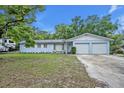 Charming single-story light blue home with an attached two-car garage and mature landscaping in the front yard at 806 Bear Lake Rd, Apopka, FL 32703