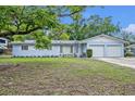Charming single-story light blue home with an attached two-car garage, flower beds, and mature landscaping in the front yard at 806 Bear Lake Rd, Apopka, FL 32703