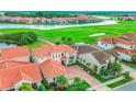 An aerial view of a neighborhood showcasing homes with terracotta roofs, lush green lawns, and serene water features at 13125 Alderley Dr, Orlando, FL 32832