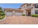 Front exterior featuring a three-car garage, brick paver driveway, and manicured landscaping at 13125 Alderley Dr, Orlando, FL 32832