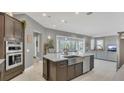 Open kitchen design with an island, stainless steel sink, and modern appliances overlooking living area at 13125 Alderley Dr, Orlando, FL 32832