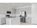 Modern kitchen featuring stainless steel appliances, gray cabinets, quartz countertops, and a central island at 2026 Firethorn Loop, Haines City, FL 33844