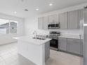 Modern kitchen with stainless steel appliances, quartz countertops, a center island, and gray cabinets at 2026 Firethorn Loop, Haines City, FL 33844