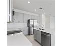 Modern kitchen featuring stainless steel appliances, gray cabinets, quartz countertops, and a center island at 2026 Firethorn Loop, Haines City, FL 33844