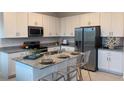 Modern kitchen with stainless steel appliances, granite countertops, island seating, and ample cabinet space at 2026 Firethorn Loop, Haines City, FL 33844