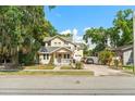 Inviting two-story home with a charming front porch, lush landscaping, and a brick driveway at 2223 Amherst Ave, Orlando, FL 32804