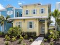 Charming two-story yellow beach home with light blue shutters, landscaped yard, and walkway to the front door at 3036 Parrot Head Pl, Kissimmee, FL 34747