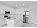 Modern kitchen features white cabinetry, stainless steel appliances, and a center island at 499 Silver Palm Dr, Haines City, FL 33844