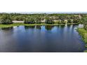 Scenic aerial view of a serene lake surrounded by lush greenery and distant residential areas under a partly cloudy sky at 612 Heron Bay Dr, Orlando, FL 32825