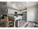Bright kitchen featuring sleek stainless steel appliances, white cabinets, peninsula counter seating, and stylish gray wood flooring at 612 Heron Bay Dr, Orlando, FL 32825