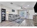 Comfortable living room with wood-look floors, gray sectional, and abundant natural light at 7033 Budapest Way, Orlando, FL 32822