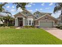 Inviting two-story home with stone accents, lush lawn, and a brick driveway leading to an attached garage at 724 Duff Dr, Winter Garden, FL 34787