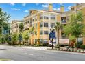 A bright yellow apartment building complex with palm trees and mature shade trees along a city street at 860 N Orange Ave # 323, Orlando, FL 32801