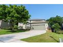 Home featuring a well-kept lawn, mature trees, and an attached two-car garage at 1161 Coastal Cir, Ocoee, FL 34761
