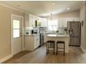 Modern kitchen featuring white cabinets, stainless steel appliances, island with stool seating, and updated fixtures at 1220 Dustin Dr, Lady Lake, FL 32159