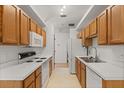 Galley kitchen featuring wooden cabinets, white appliances and white countertops at 1415 Hensley Dr, Deland, FL 32724