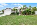 Inviting single-story home showcasing lush landscaping, including palm trees and tropical plants, with green lawn at 145 Henue Ct, Davenport, FL 33896