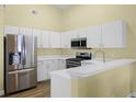 Bright kitchen featuring stainless steel appliances, white cabinets, and a convenient breakfast bar at 145 Henue Ct, Davenport, FL 33896