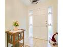 Bright entryway with white tile flooring, a wooden accent table, and a white front door with side windows at 2095 Curry Ln, Orlando, FL 32812